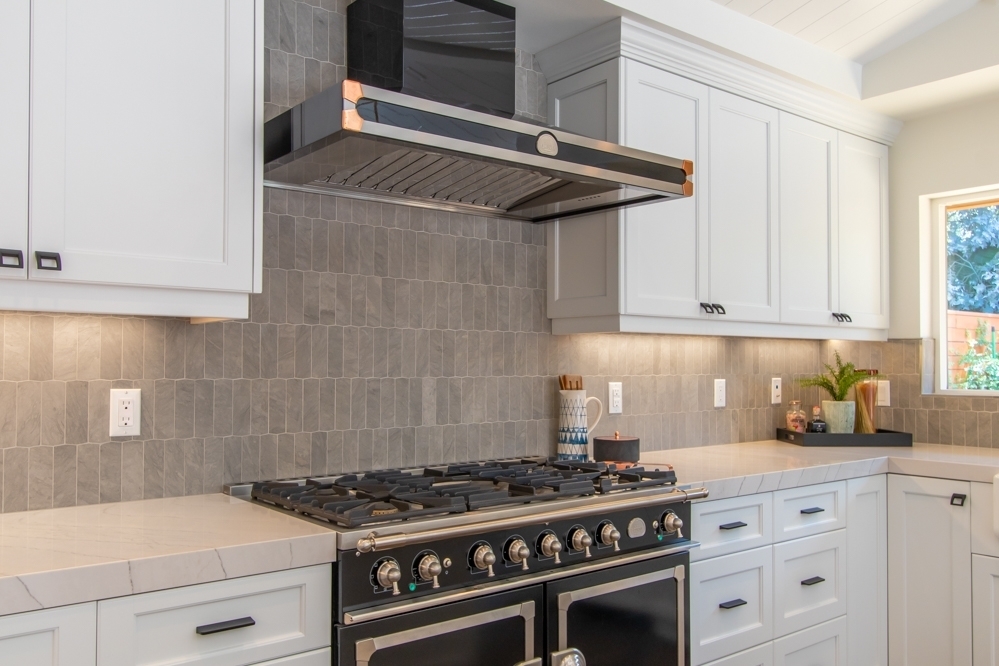 kitchen with white cabinets, quartzite countertops and grey full height tile backsplash
