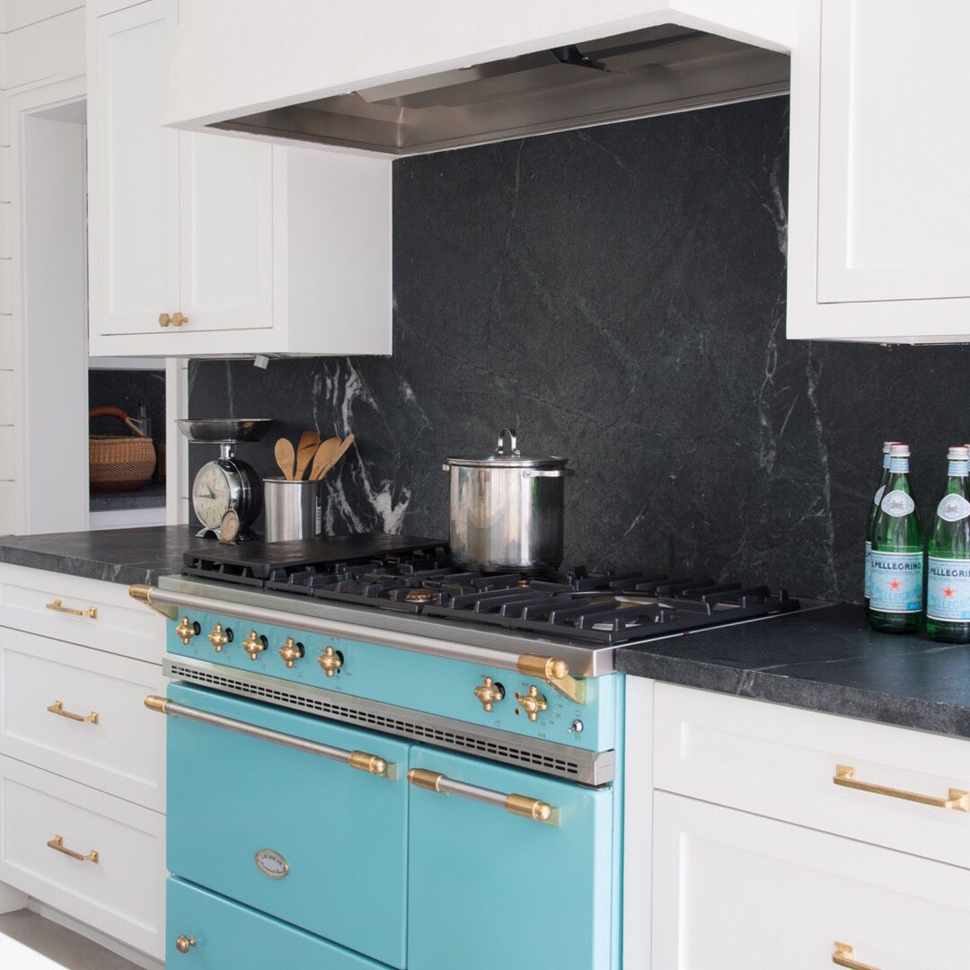 black soapstone countertops with full height backsplash behind blue stove