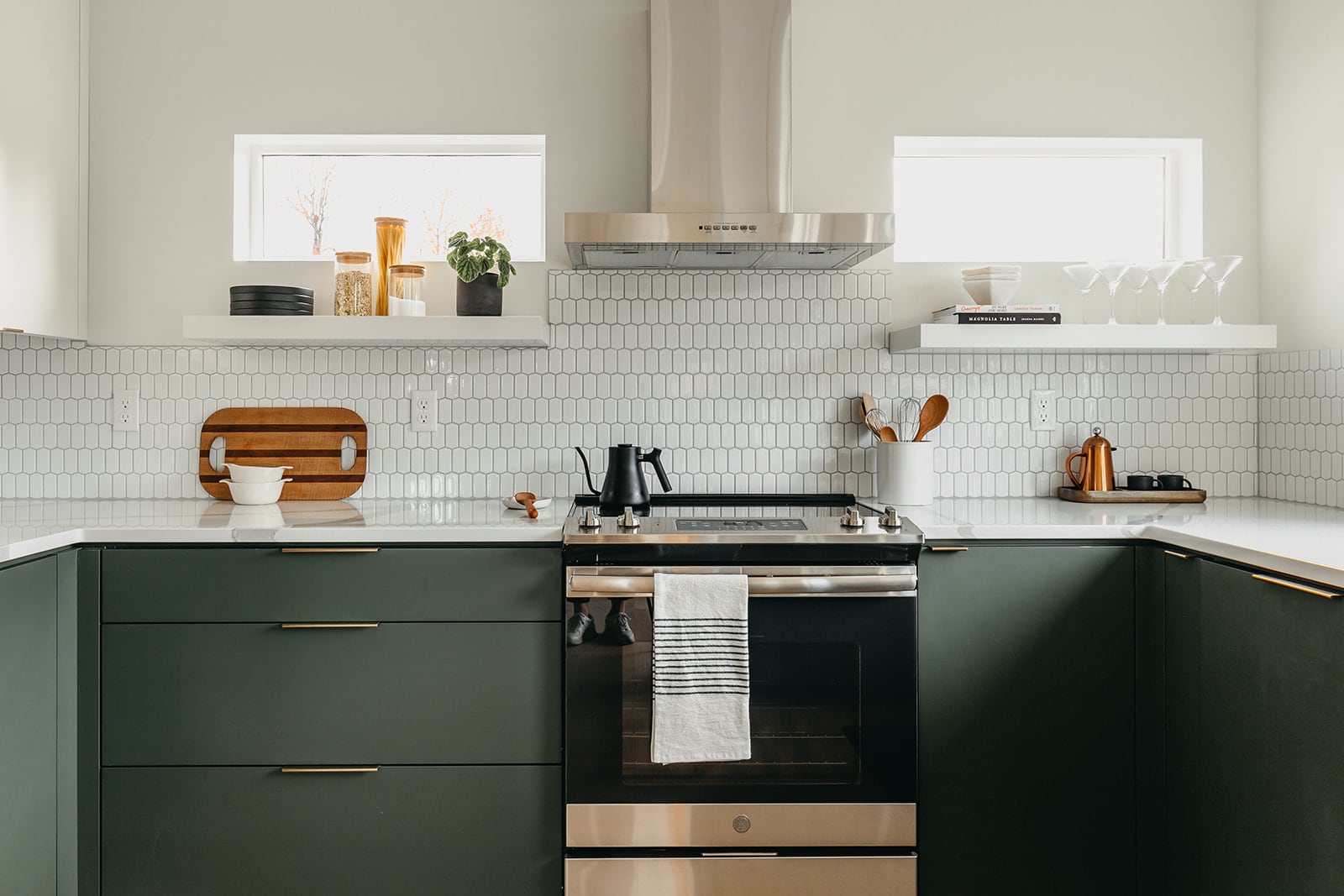 green kitchen cabinets with white quartz countertops and full height white tile backsplash