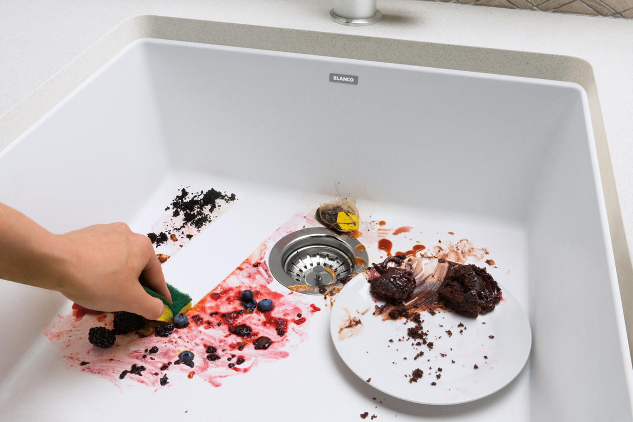 fireclay white farmhouse sink being cleaned of food and dishes