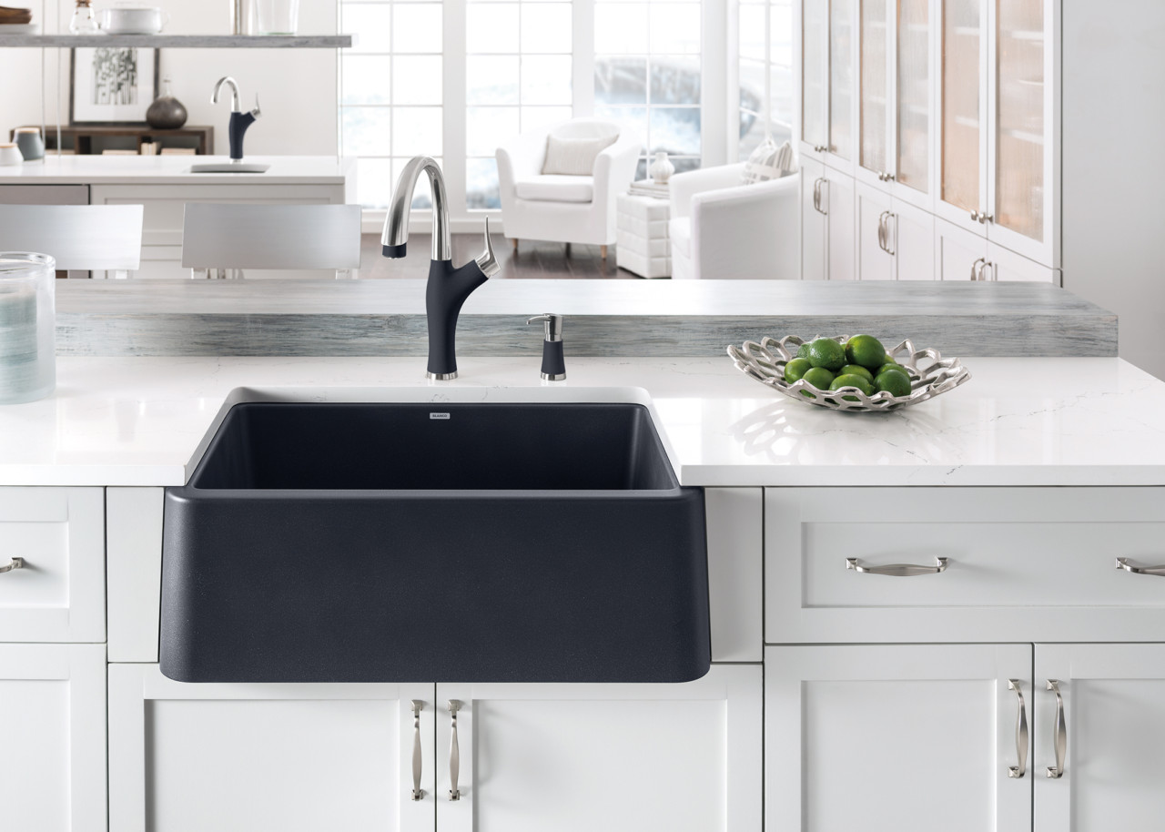 black composite farmhouse sink in kitchen with white cabinets and white countertops