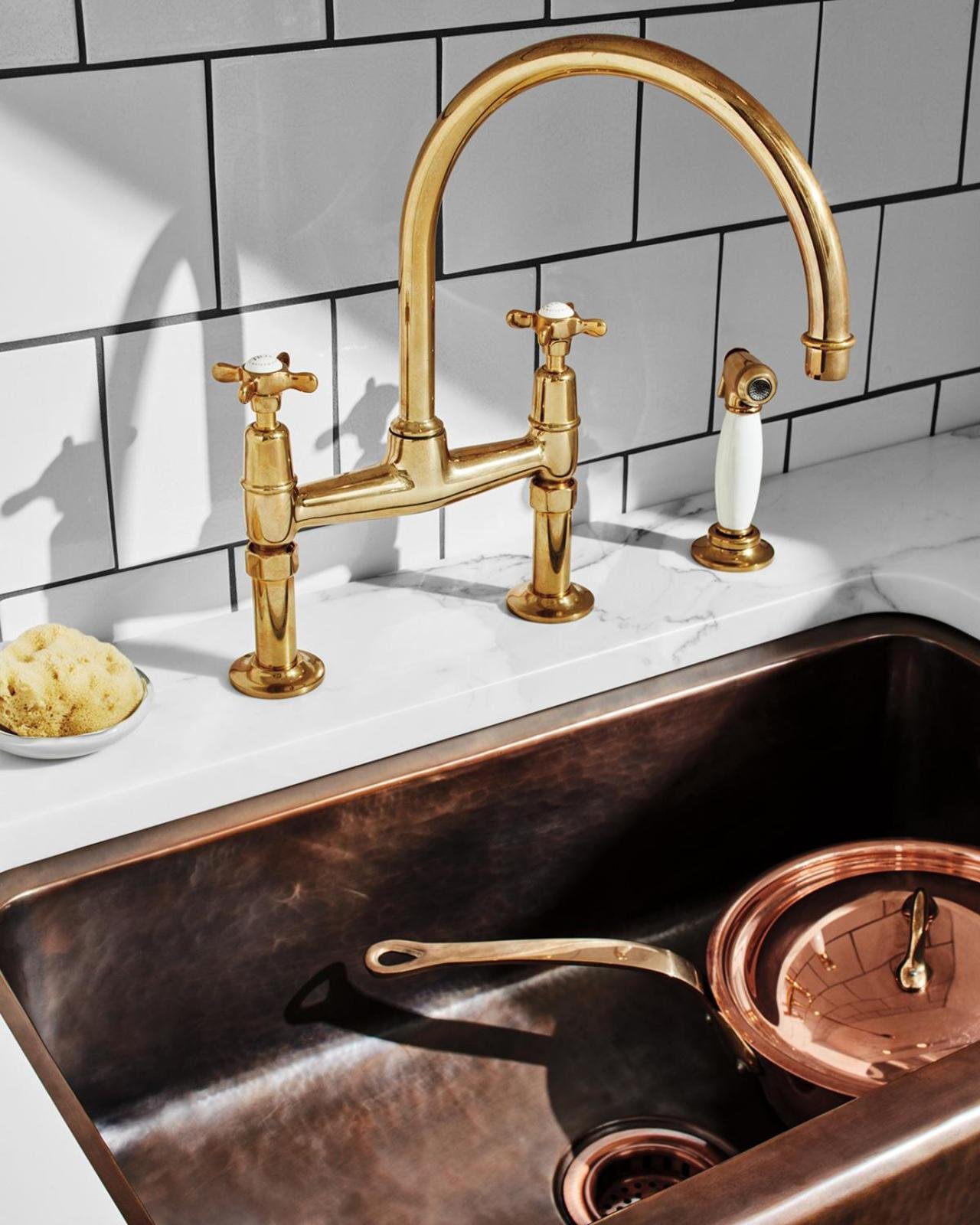 copper farmhouse sink with gold faucets and white countertops
