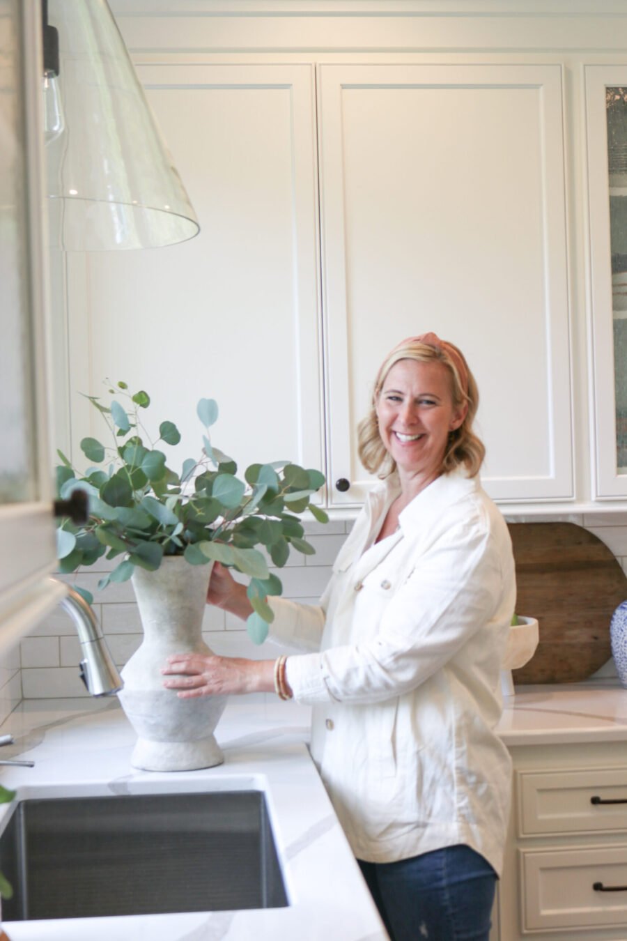 happy woman in remodeled kitchen with plant at undermount sink