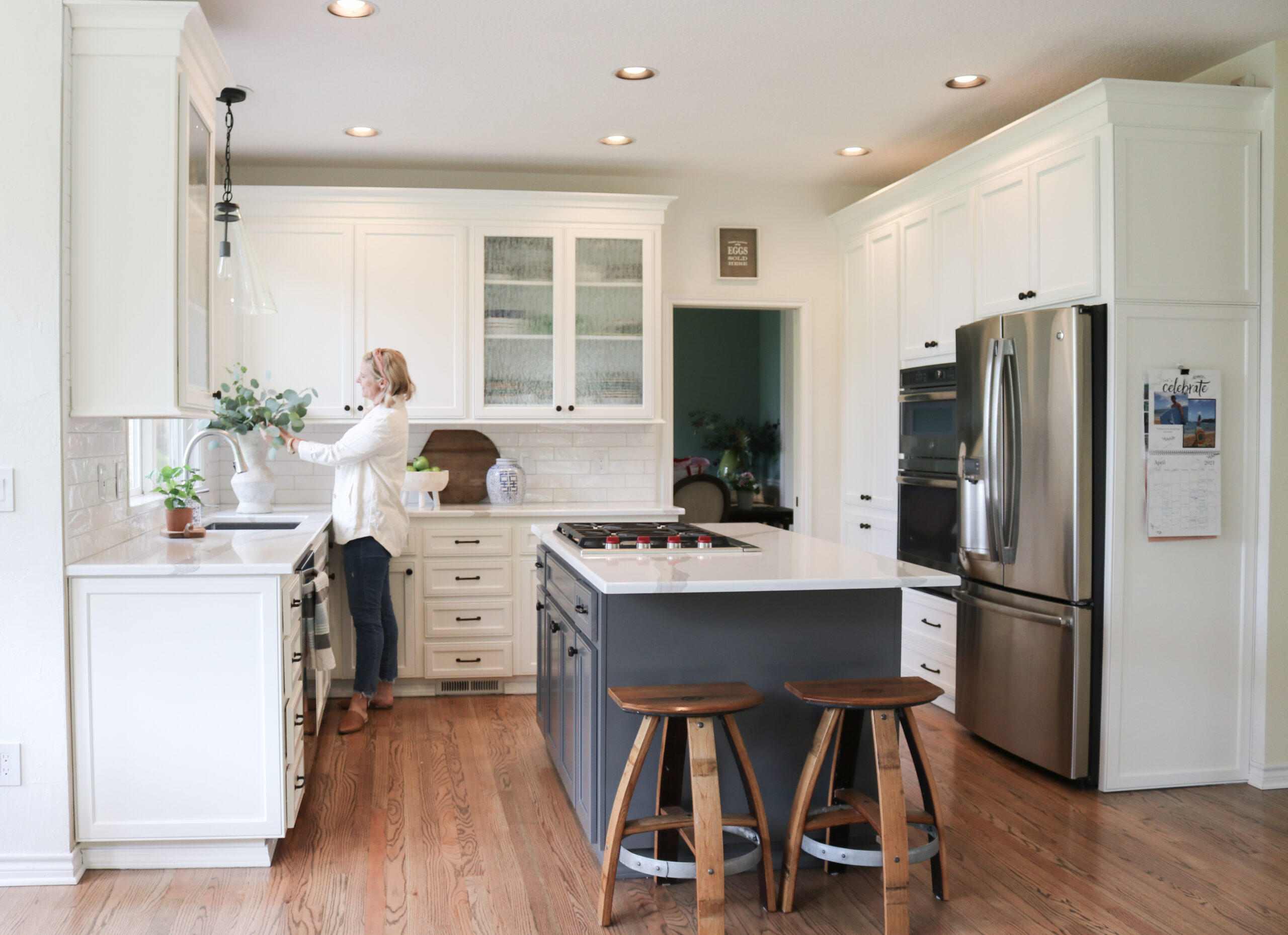 woman watering a plant in the kitchen with Arabescatto quartz countertops