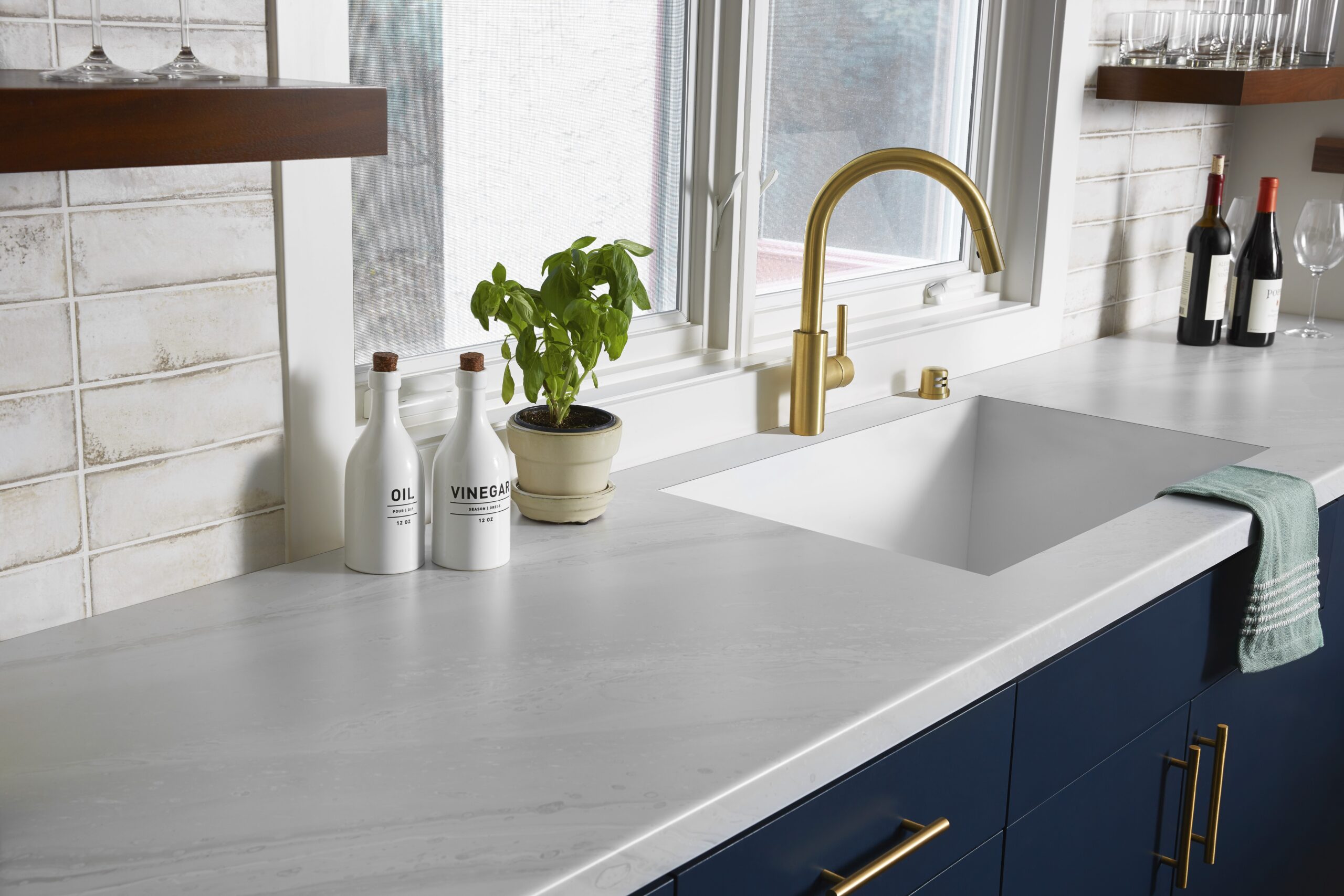 carrara marble kitchen countertop, navy blue cabinets, gold faucet open wood shelves