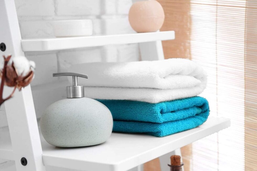 Soap dispenser and towels on a bathroom shelf