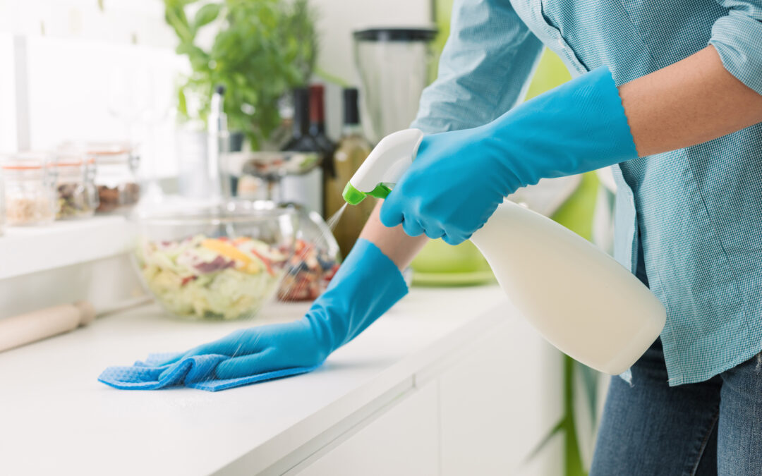 Woman cleaning and polishing the kitchen quartz countertop with a spray detergent,